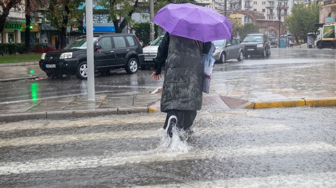 Γυναίκα με ομπρέλα σε πλημμυρισμένο δρόμο 
