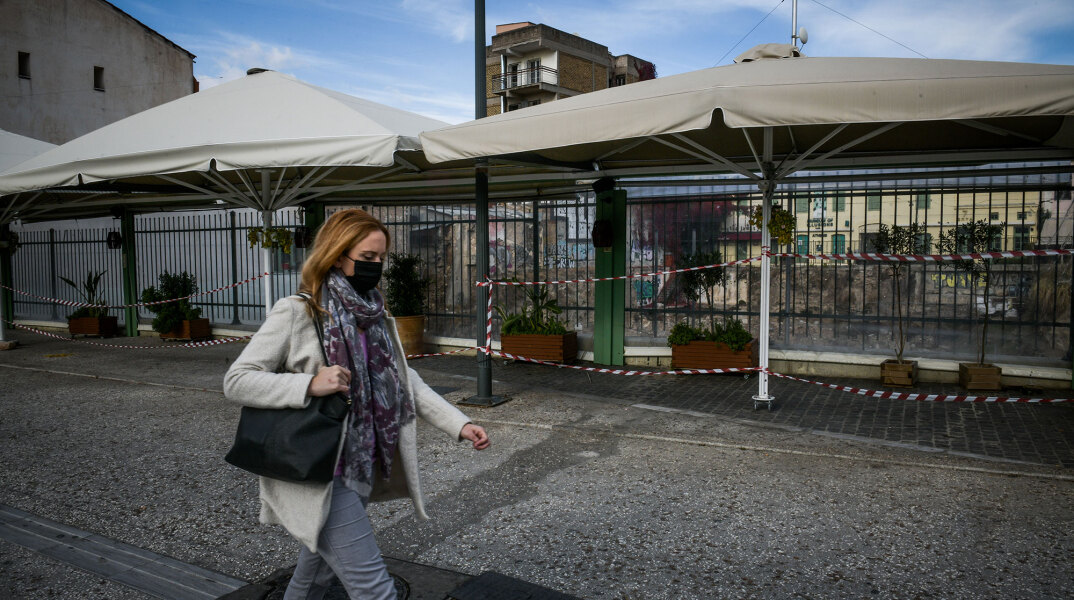 Γυναίκα με μάσκα για τον κορωνοϊό διασχίζει πεζόδρομο στο κέντρο της Αθήνας εν μέσω lockdown