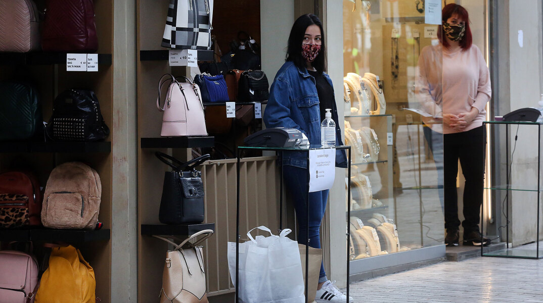 Click away και εμπορικά καταστήματα: Με μάσκα για τον κορωνοϊό και αντισηπτικό, πωλήτρια περιμένει σε ειδική θέση στην είσοδο τον καταναλωτή για την παράδοση του προϊόντος