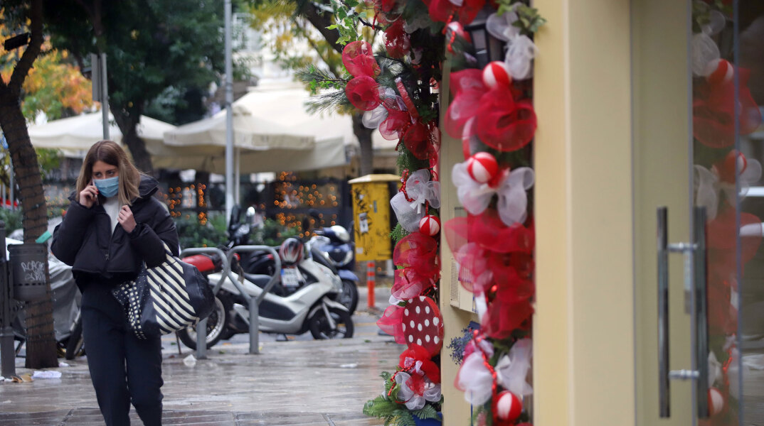 Γυναίκα μιλά στο κινητό έξω από κατάστημα με χριστουγεννιάτικα στη Θεσσαλονίκη