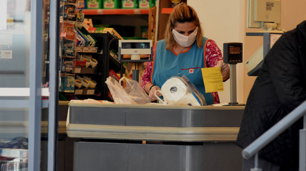 Εργαζόμενη με προστατευτική μάσκα για τον κορωνοϊό σε σούπερ μάρκετ