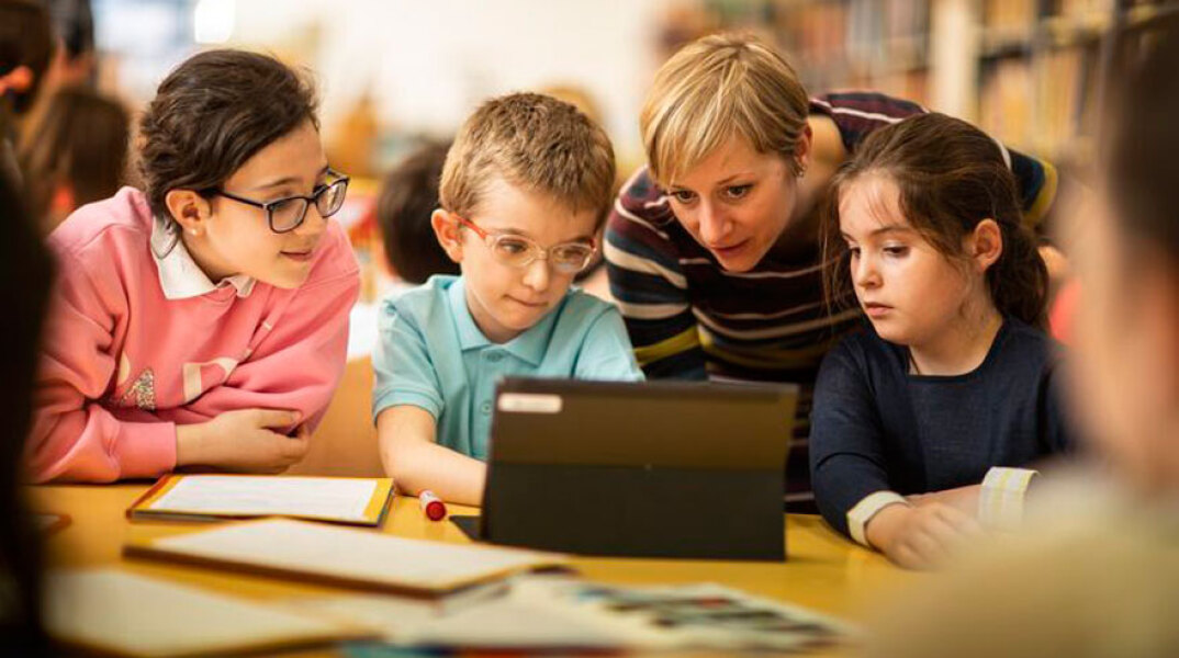 Ομάδα παιδιών και δασκάλων μπροστά σε υπολογιστή