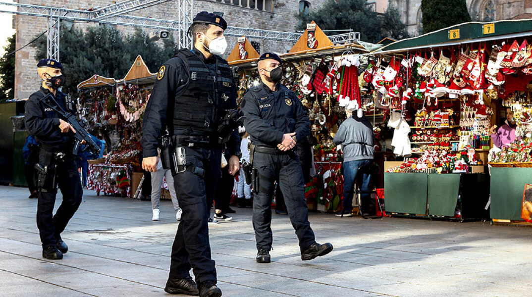 Αστυνομικοί με μάσκα για τον κορωνοϊό περιπολούν σε υπαίθρια αγορά με χριστουγεννιάτικα είδη στη Βαρκελώνη