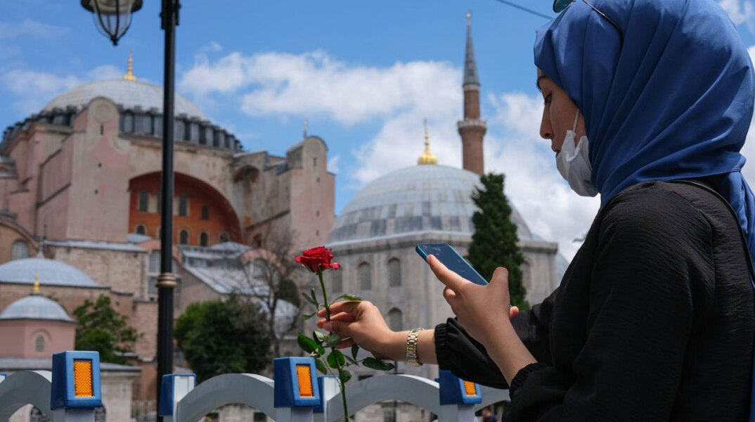 Γυναίκα με μαντήλα και μάσκα για τον κορωνοϊό αφήνει ένα κόκκινο τριαντάφυλλο μπροστά στην Αγία Σοφία στην Κωνσταντινούπολη