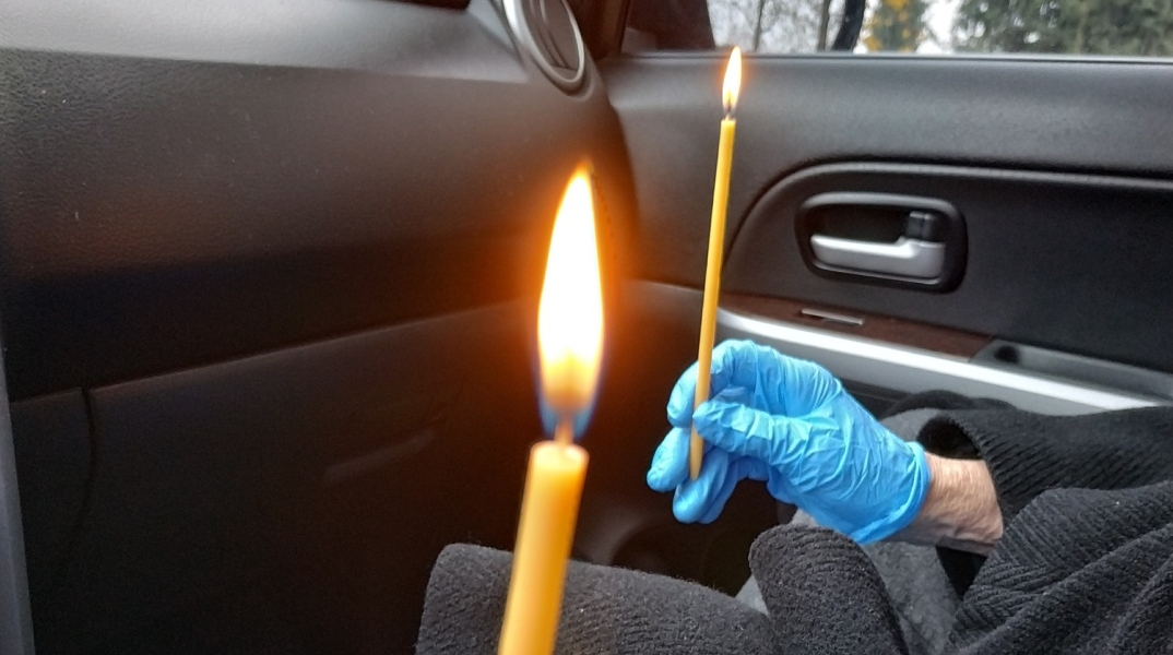 Χέρια που κρατούν αναμμένα κεριά μέσα σε αυτοκίνητο