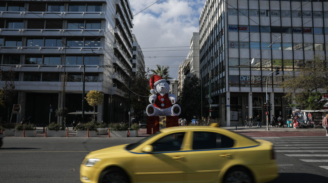 Πλατεία Συντάγματος: Ταξί περνά μπροστά από τον χριστουγεννιάτικο αρκούδο στην αρχή της Ερμού