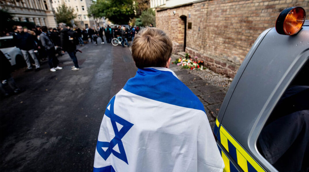 Νεαρός με τη σημαία του Ισραήλ στην πλάτη μπροστά από την εβραϊκή συναγωγή στη γερμανική πόλη Χάλλε