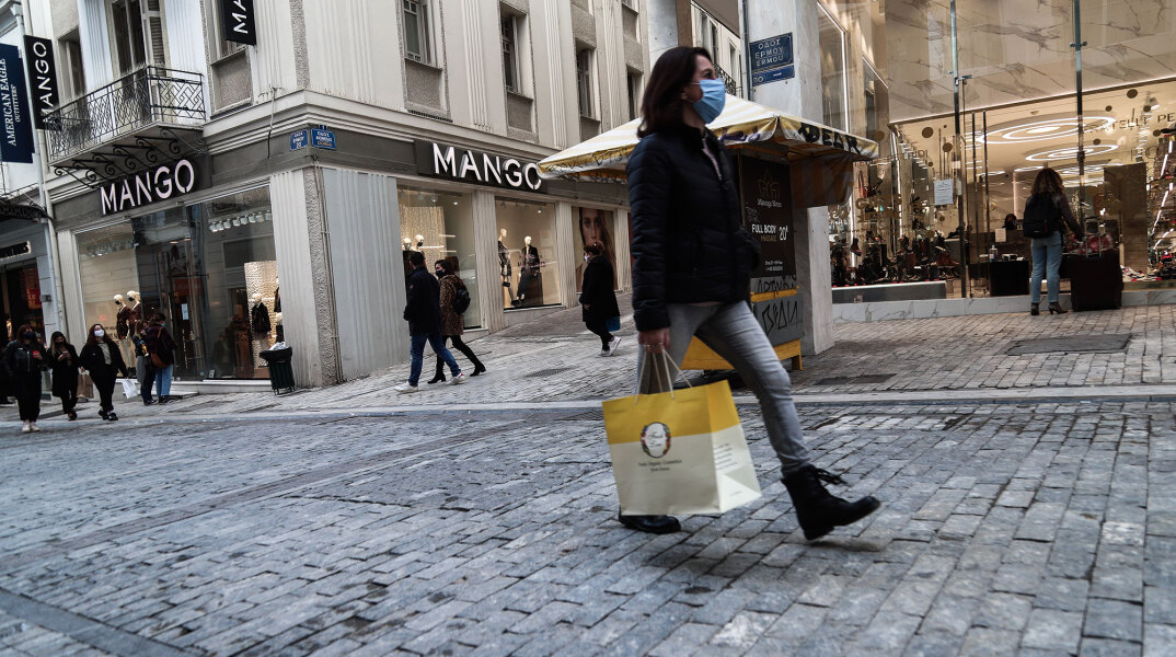 Γυναίκα με μάσκα για τον κορωνοϊό και τσάντα με ψώνια στην Ερμού, δύο ημέρες πριν από τα Χριστούγεννα 2020