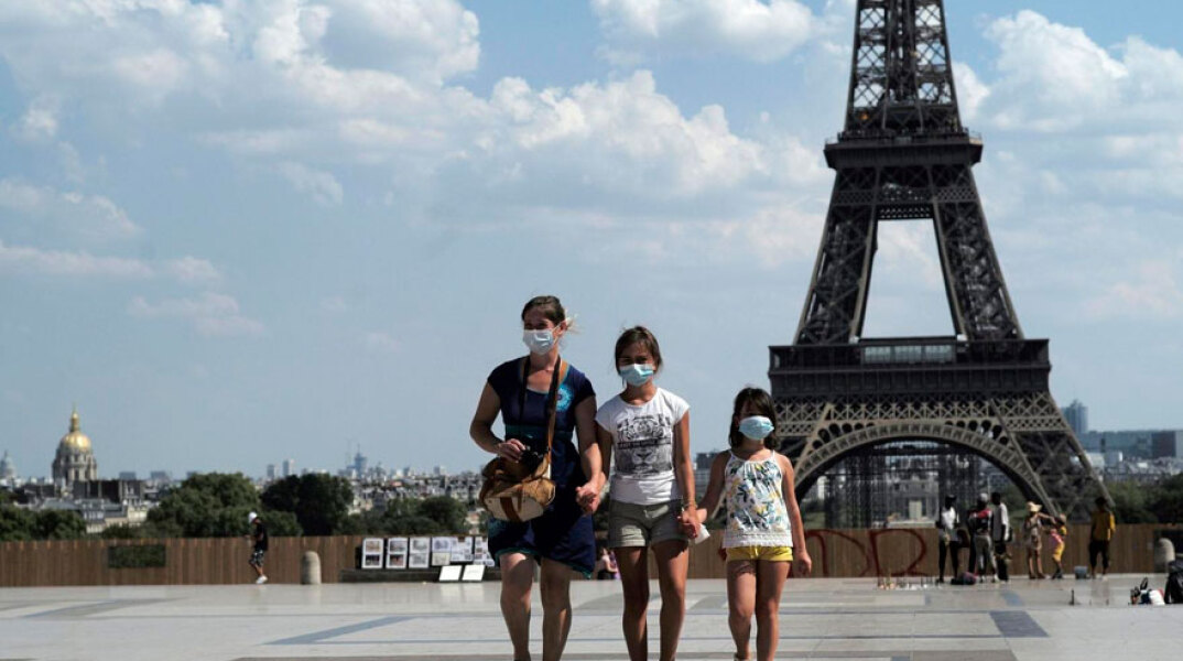 Γαλλία: Τουρίστες με μάσκες για τον κορωνοϊό με φόντο τον Πύργο του Άιφελ στο Παρίσι