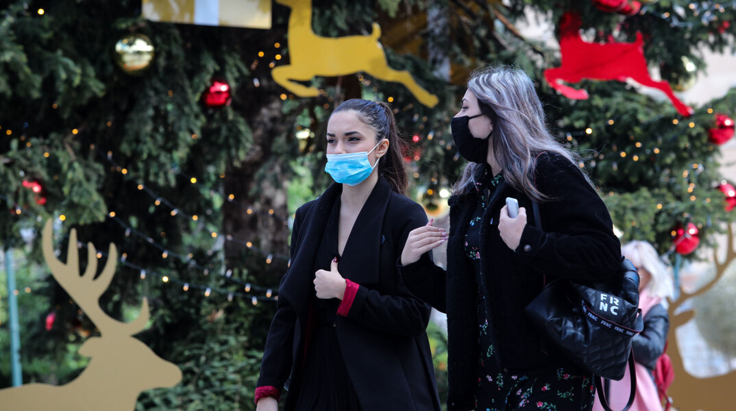 Πλατεία Συντάγματος - Lockdown: Δύο γυναίκες με μάσκα για τον κορωνοϊό περνούν μπροστά από το χριστουγεννιάτικο δέντρο