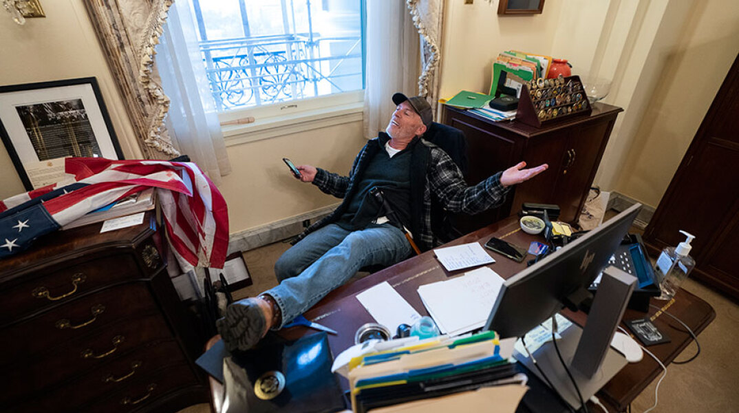 Εισβολή στο Καπιτώλιο: Ένας από τους υποστηρικτές του Ντόναλντ Τραμπ που εισέβαλε στο κτίριο, με το πόδι στο γραφείο και το κινητό ανά χείρας