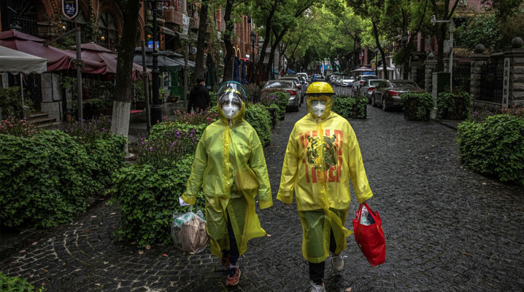 Πολίτες στην Κίνα με προστατευτικές στολές και μάσκες για τον κορωνοϊό