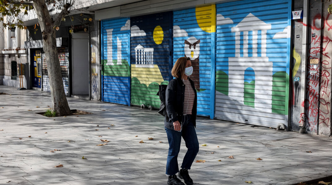 Γυναίκα με μάσκα για τον κορωνοϊό στο κέντρο της Αθήνας - Στο πίσω μέρος κλειστό κατάστημα λόγω lockdown για τον κορωνοϊό