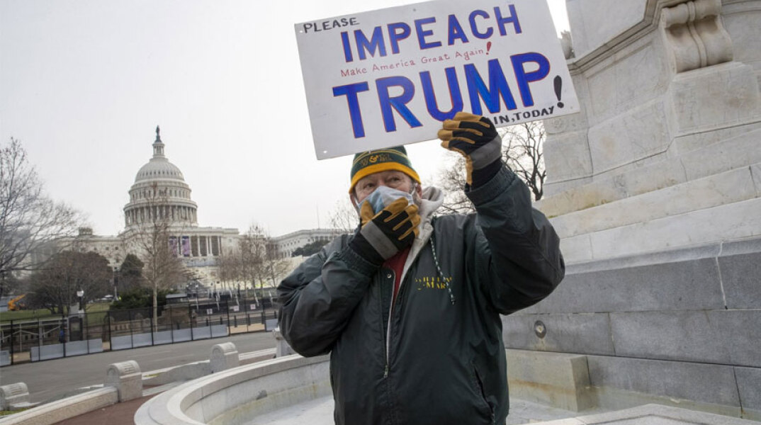 Άνδρας με μάσκα για τον κορωνοϊό ζητά την παραπομπή Τραμπ με φόντο το Καπιτώλιο