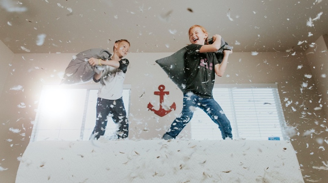 Παιδιά παίζουν μαξιλαροπόλεμο μέσα στο σπίτι