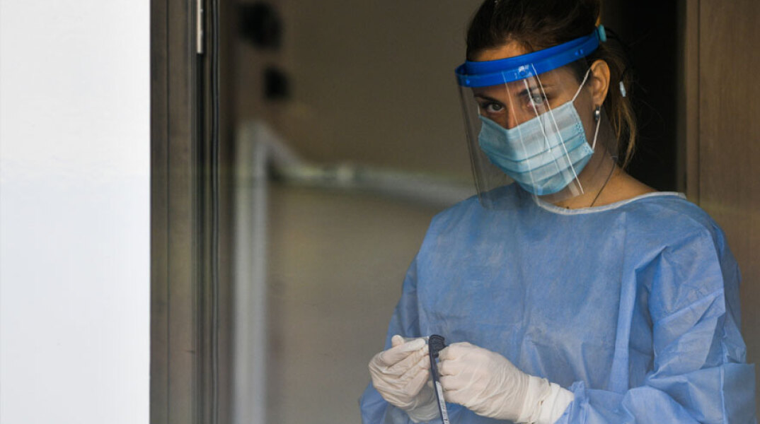 Εργαζόμενη σε κλιμάκιο του ΕΟΔΥ διενεργεί έλεγχο σε δείγμα για κορωνοϊό