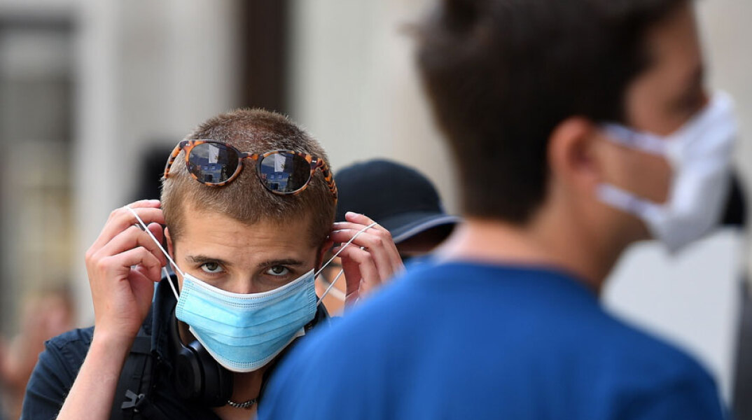 Νεαρός φορά απλή χειρουργική μάσκα για τον κορωνοϊό