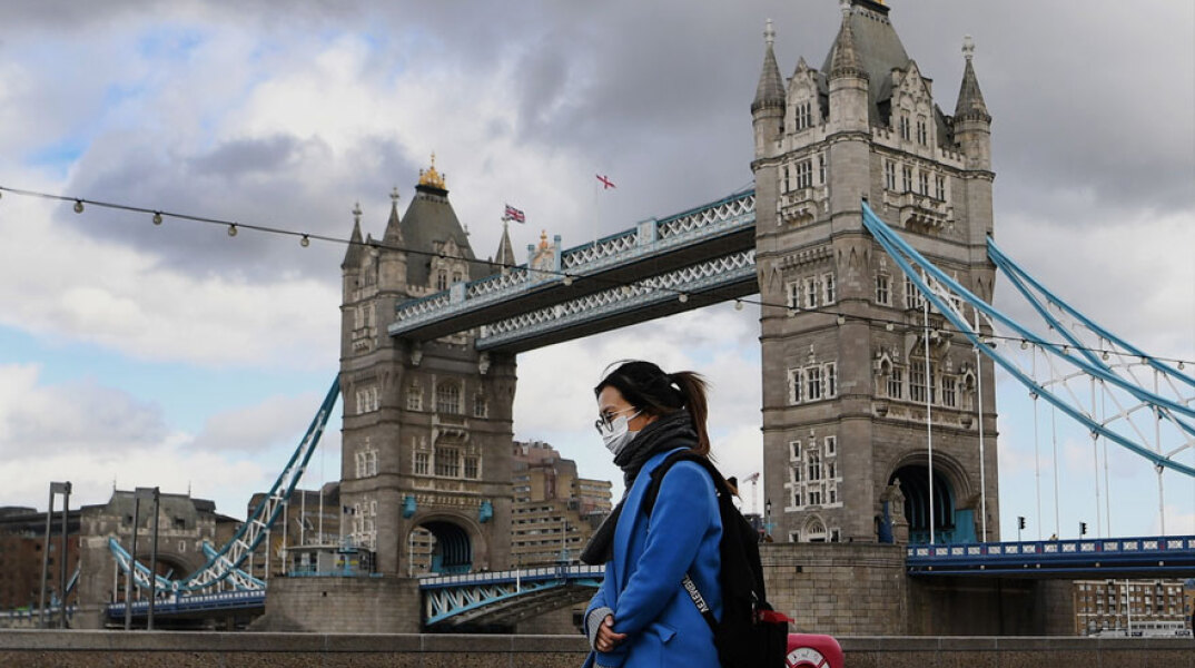 Κορωνοϊός στη Μεγάλη Βρετανία: Κοπέλα φορά μάσκα για Covid-19 με φόντο τη Γέφυρα του Λονδίνου