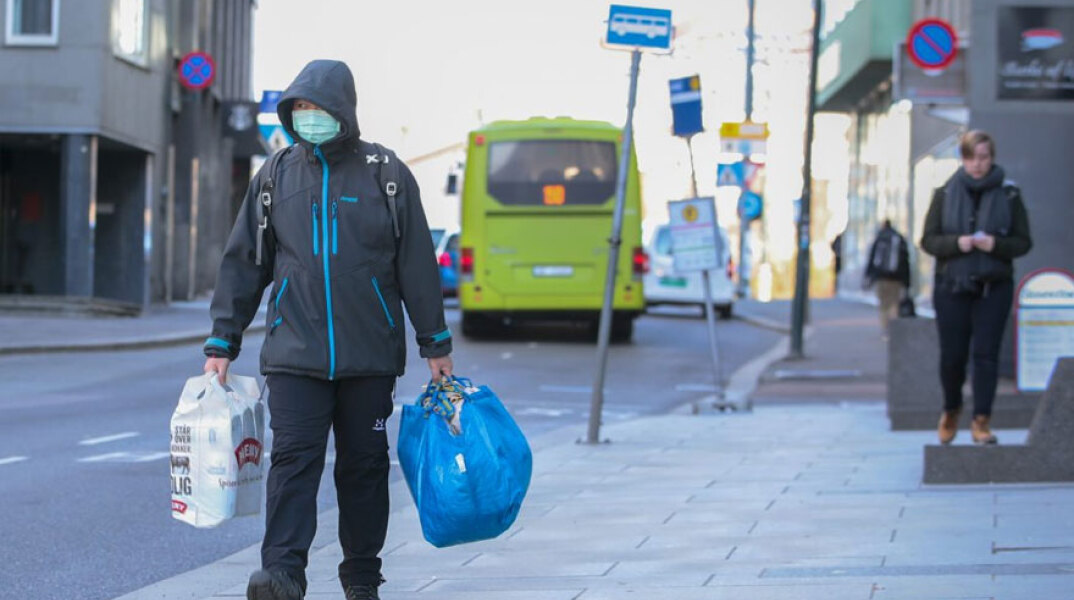 Νορβηγία: Άνδρας με μάσκα για τον κορωνοϊό κρατά σακούλες με ψώνια στην πρωτεύουσα Όσλο