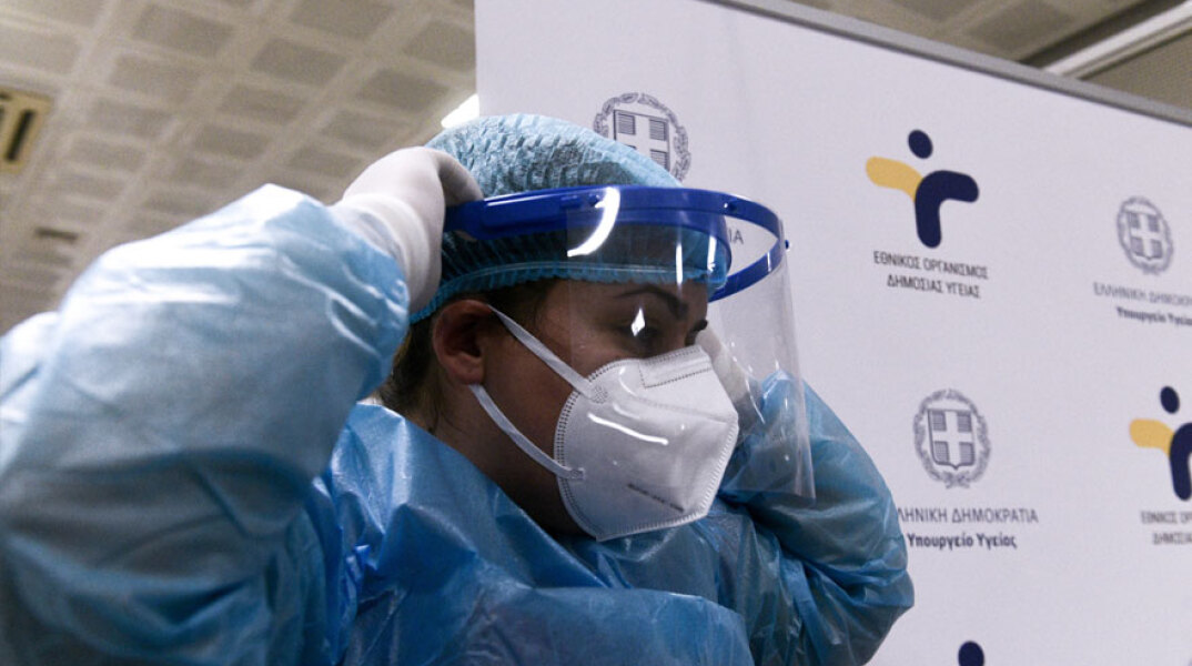 Υγειονομικός του ΕΟΔΥ με μάσκα για τον κορωνοϊό και προστατευτική ασπίδα στο πρόσωπο σε έλεγχο για Covid-19 με rapid test