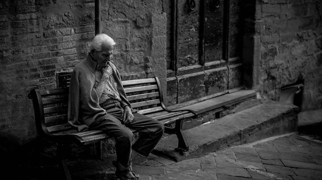 Ηλικιωμένος άνδρας που κάθεται σε παγκάκι