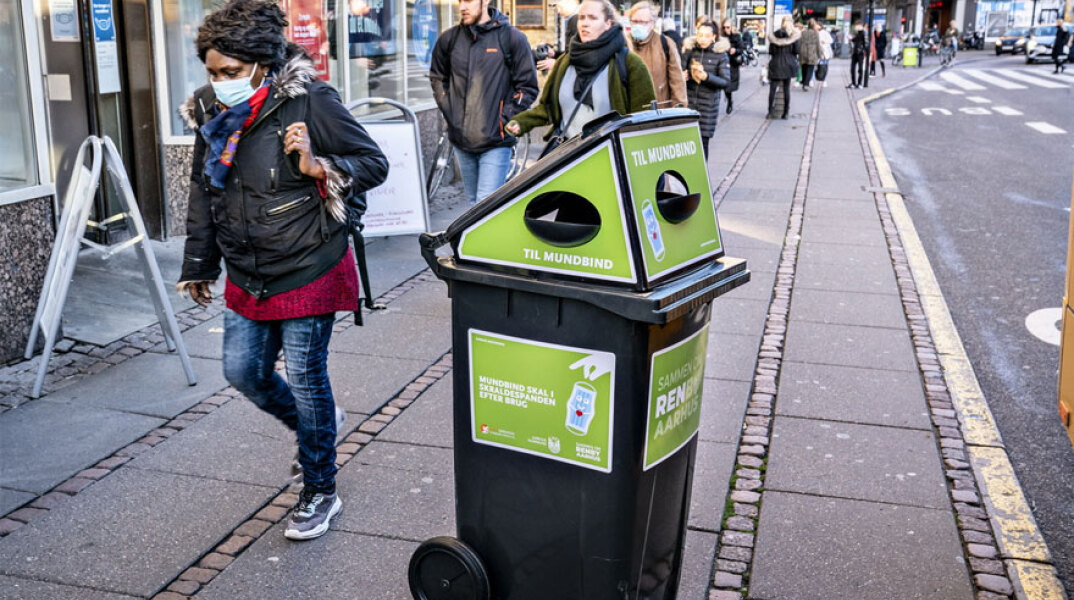 Κορωνοϊός - Δανία: Γυναίκα με προστατευτική μάσκα για τον κορωνοϊό περπατά σε δρόμο στην πρωτεύουσα Κοπεγχάγη
