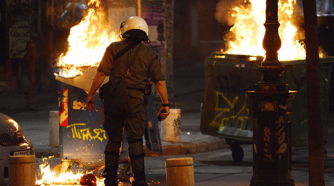 Επεισόδια στη Θεσσαλονίκη - Αστυνομικός μπροστά σε κάδους που έχουν παραδοθεί στις φλόγες (ΦΩΤΟ ΑΡΧΕΙΟΥ)