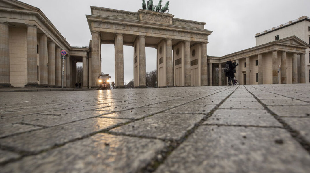 Γερμανία - Κορωνοϊός: Νεαρός με μάσκα για τον κορωνοϊό μπροστά από την Πύλη του Βραδεμβούργου στο Βερολίνο