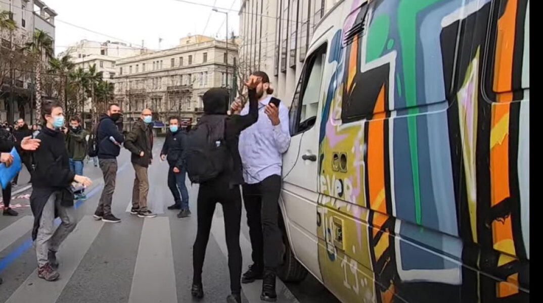 Ο Έλληνας ράπερ Ν.Ο.Ε δέχεται επίθεση για να αφήσει το μικρόφωνο και να μην εκφράσει τη γνώμη του σε πορεία για την ελευθερία του λόγου στην Αθήνα