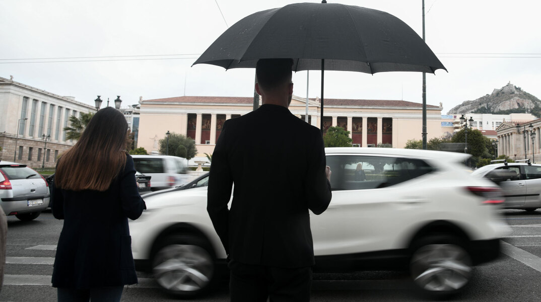 Lockdown στην Αττική: Νεαρός με ομπρέλα στη βροχερή Αθήνα