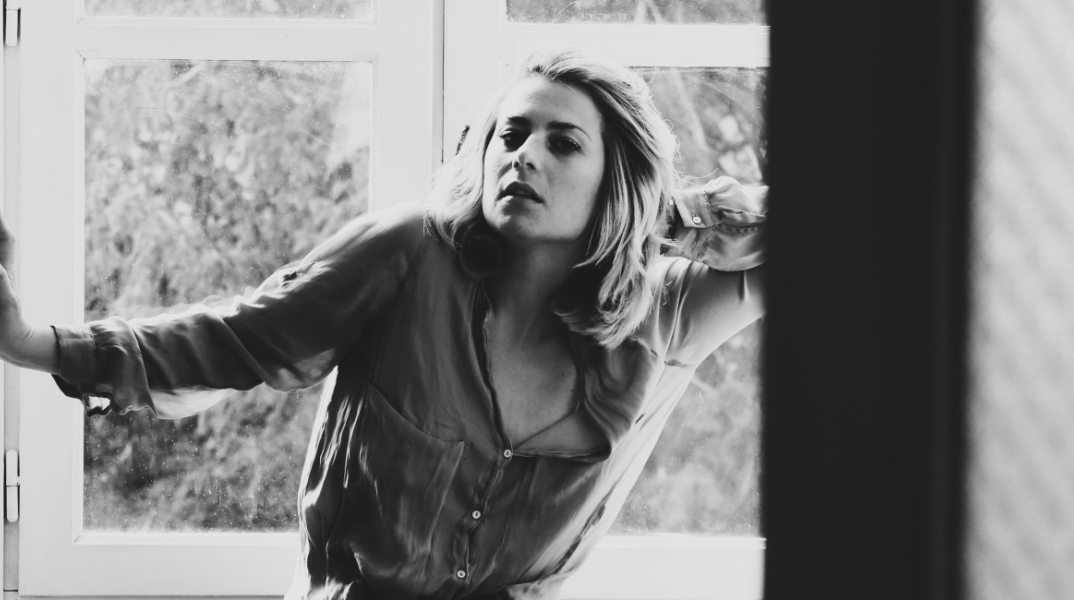 Ασπρόμαυρη γυναίκα που απεικονίζει γυναίκα να στέκεται μπροστά από το παράθυρο