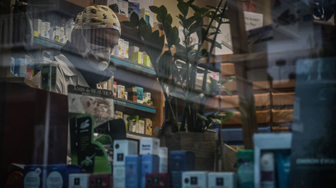 Φαρμακοποιός με μάσκα για τον κορωνοϊό σε φαρμακείο