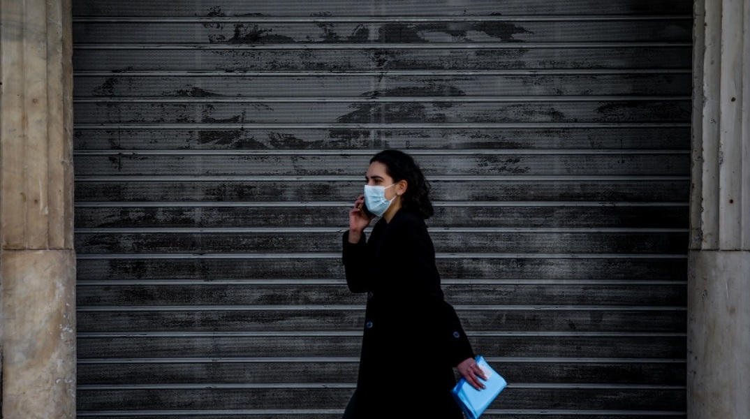 Γυναίκα με μάσκα μπροστά από κλειστό κατάστημα