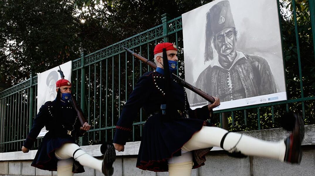 Εύζωνες της Προεδρικής Φρουράς μπροστά από την υπαίθρια έκθεση προσωπογραφιών ηρώων της επανάστασης του 1821 στην περίφραξη του Εθνικού Κήπου