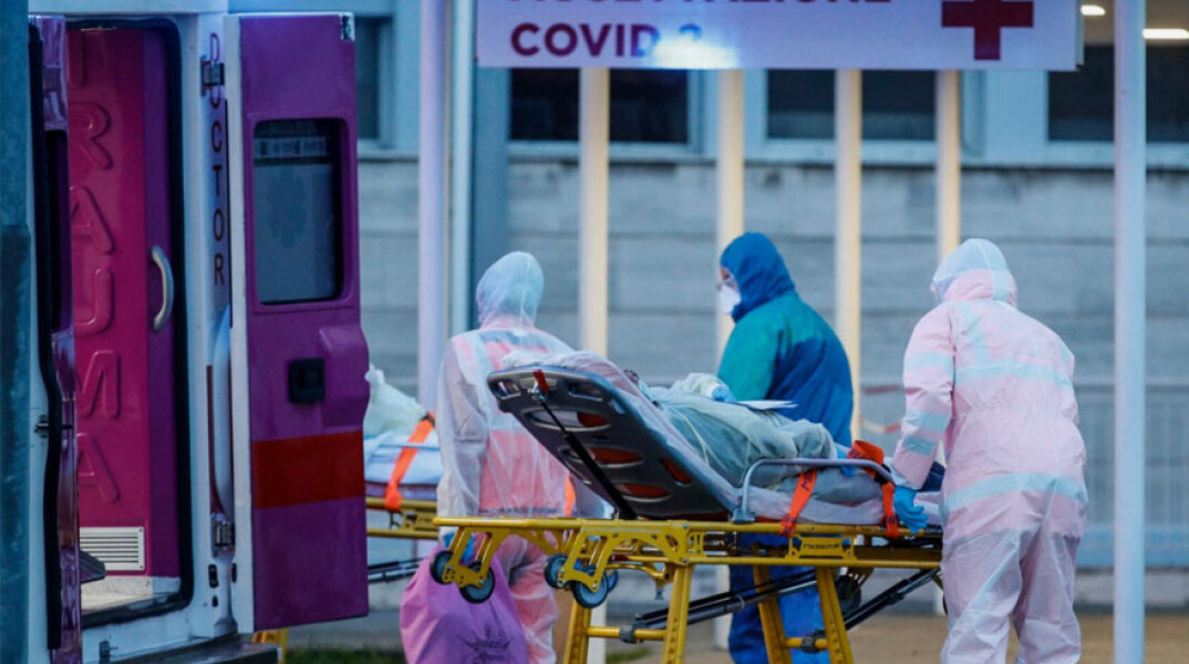 Ιταλία: Υγειονομικοί έξω από νοσοκομείο μεταφέρουν φορείο με ασθενή που έχει κορωνοϊό
