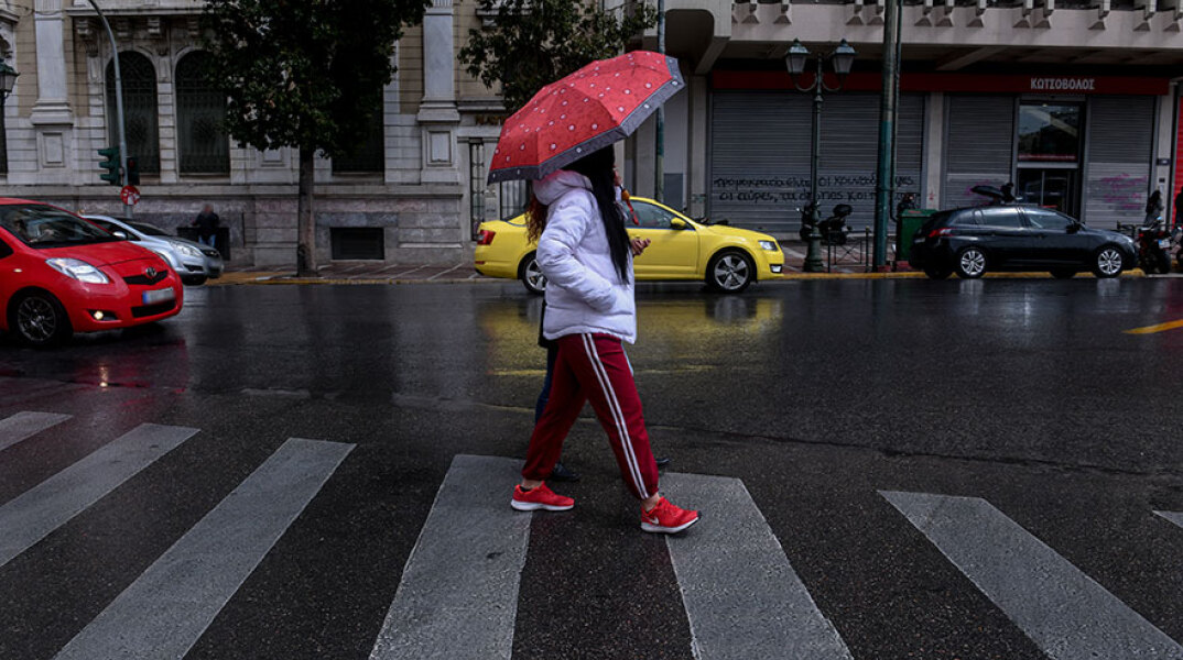 Αττική - Lockdown: Κοπέλα με ομπρέλα διασχίζει διάβαση πεζών στην Αθήνα