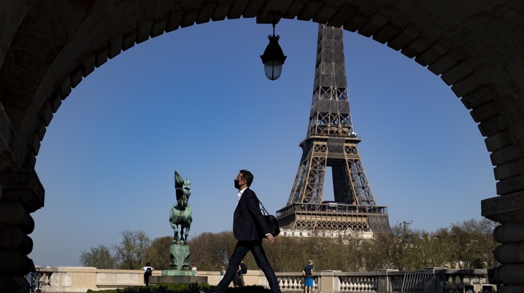 Γαλλία: Πολίτης με μάσκα περπατά με φόντο τον Πύργο του Άιφελ 