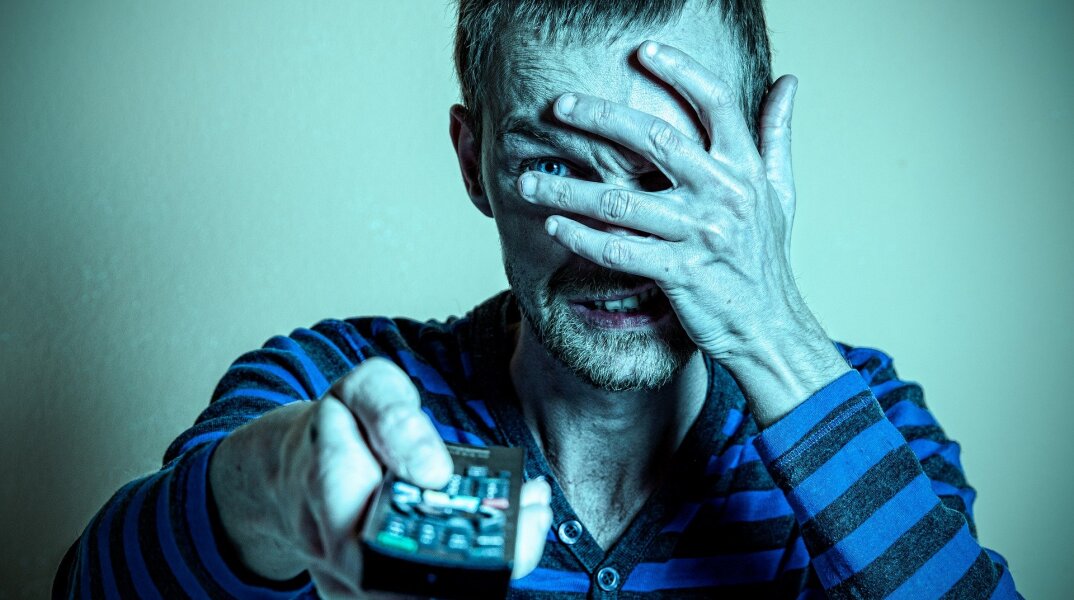 Άνδρας που κρύβει το πρόσωπό του και κρατά τηλεκοντρόλ