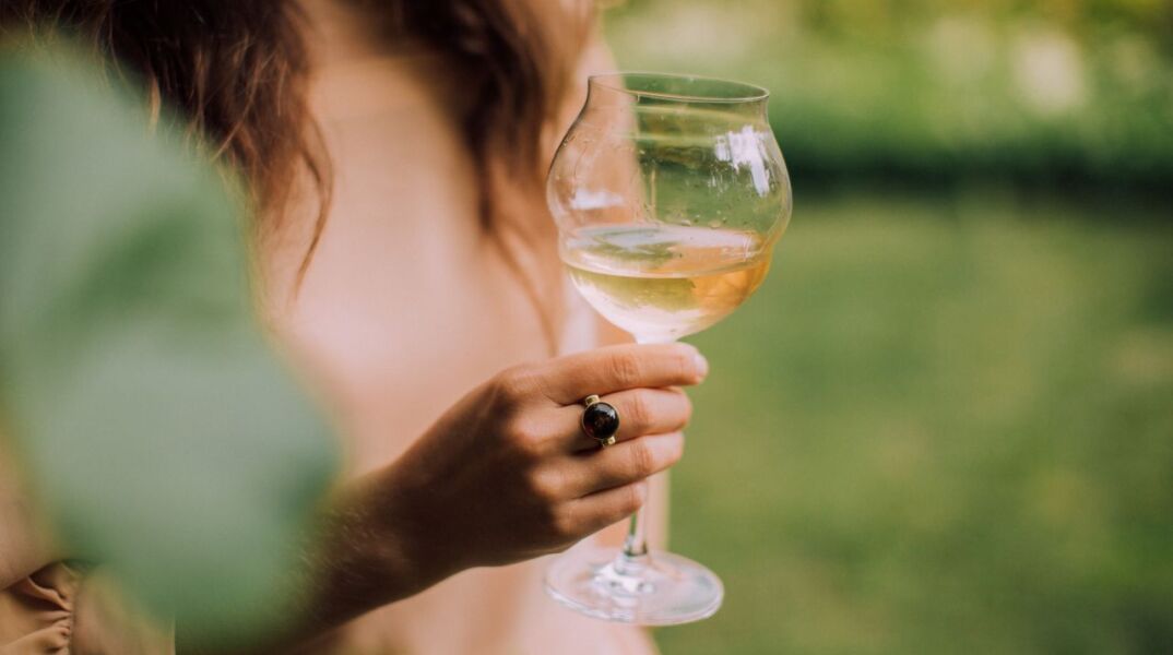 Γυναίκα που κρατάει ένα ποτήρι λευκό κρασί