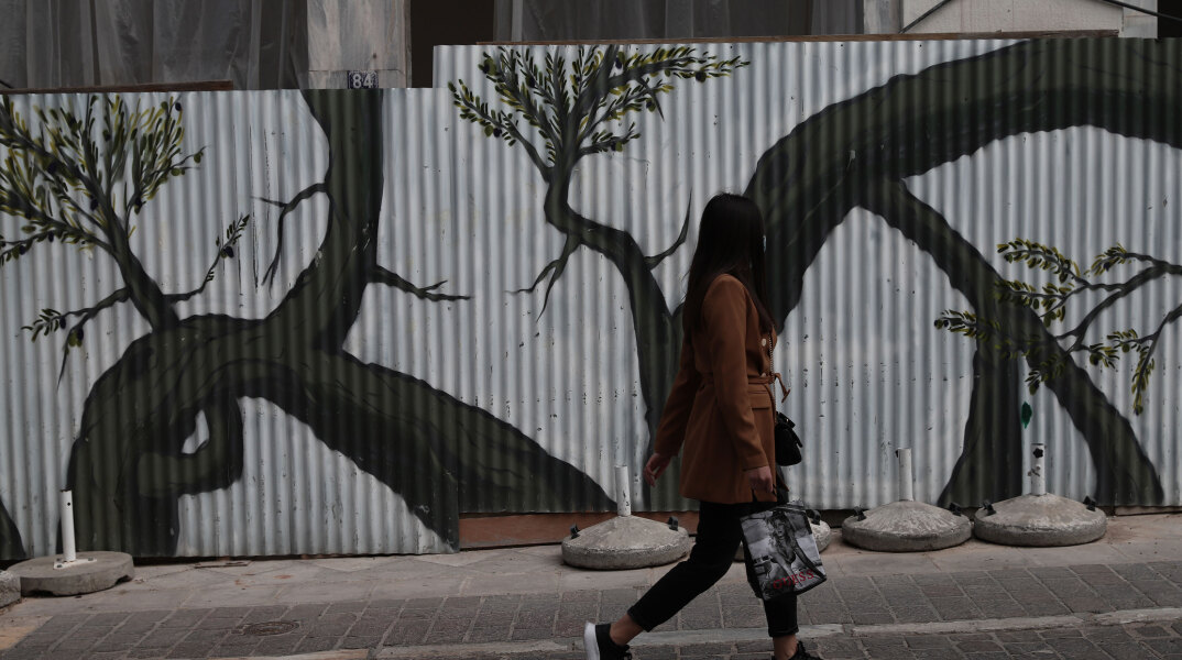 Αττική - Lockdown: Κοπέλα περνά μπροστά από γκράφιτι στο κέντρο της Αθήνας