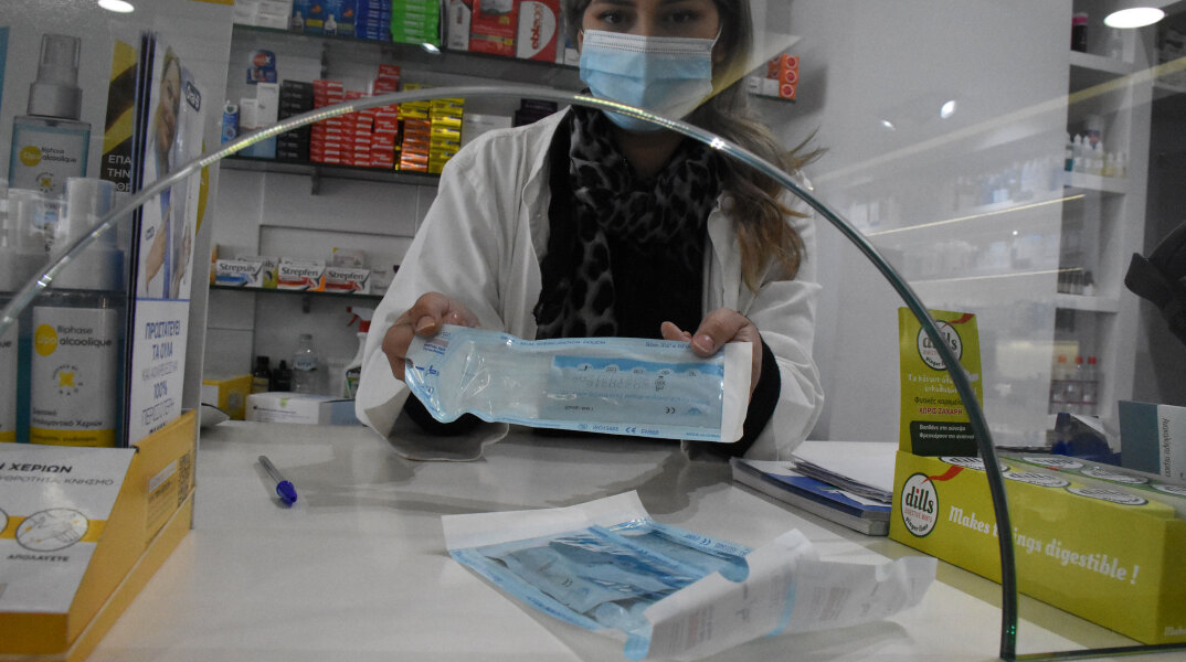 Υπάλληλος σε φαρμακείο δείχνει το self test που πρέπει να κάνουν υποχρεωτικά οι εργαζόμενοι από τη Δευτέρα 19 Απριλίου 2021