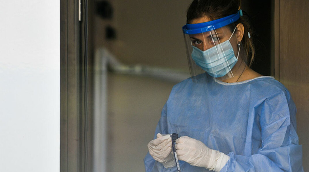 Υγειονομικός του ΕΟΔΥ με μάσκα για τον κορωνοϊό ετοιμάζει rapid test