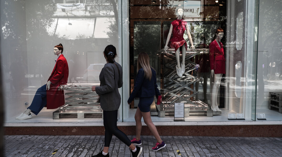 Κοπέλες περνούν έξω από εμπορικό κατάστημα στην Ερμού