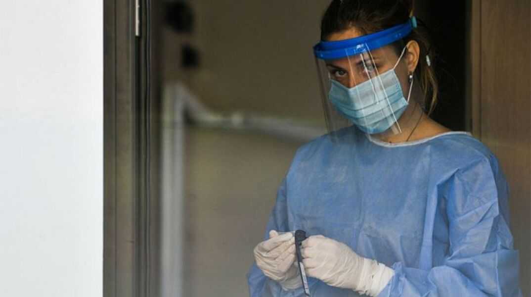Υγειονομικός του ΕΟΔΥ με μάσκα για τον κορωνοϊό ετοιμάζει rapid test