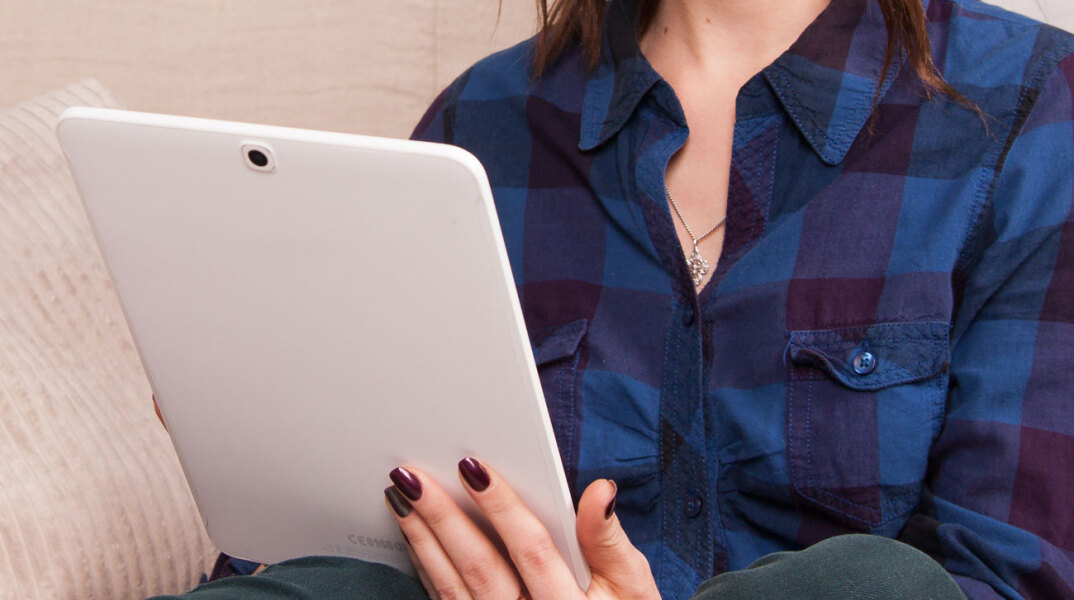 Κοπέλα με καρό πουκάμισο κρατάει τάμπλετ