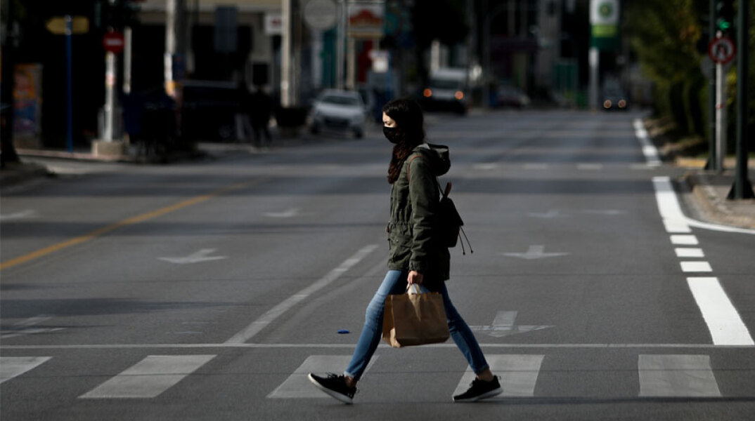 Κορωνοϊός - Ελλάδα: Γυναίκα με μάσκα διασχίζει διάβαση πεζών στην Αθήνα