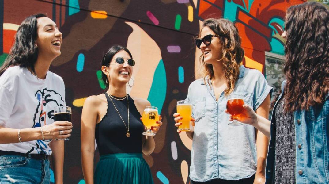 Τέσσερις φίλες που πίνουν ποτό, συζητάνε και γελάνε