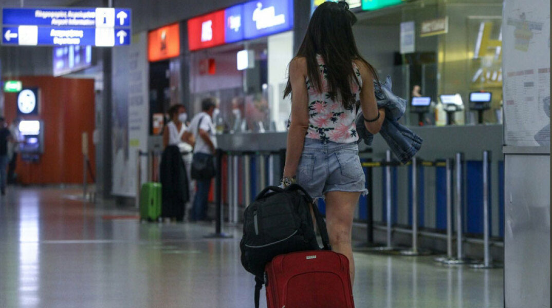 Τουρίστρια σέρνει βαλίτσα στο διεθνές αεροδρόμιο «Ελευθέριος Βενιζέλος»