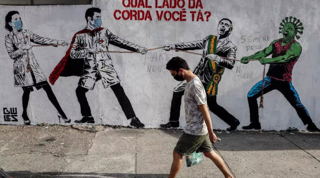 Βραζιλία: Άνδρας με μάσκα περνά μπροστά από γκράφιτι για τον κορωνοϊό - Δεύτερη παγκοσμίως σε συνολικά θύματα της πανδημίας Covid-19