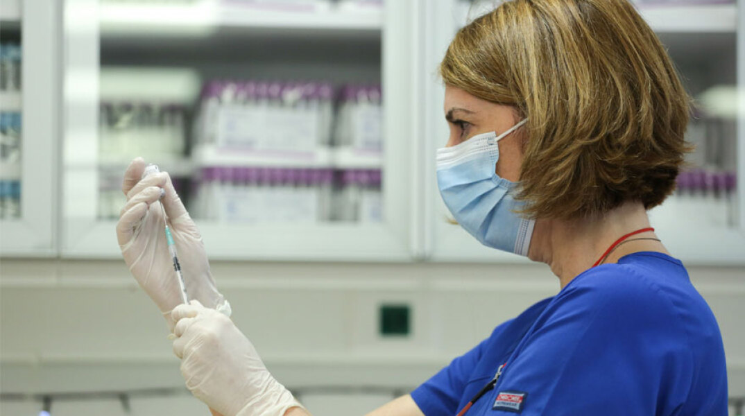 Εμβολιασμός: Υγειονομικός με μάσκα ετοιμάζει εμβόλιο για τον κορωνοϊό